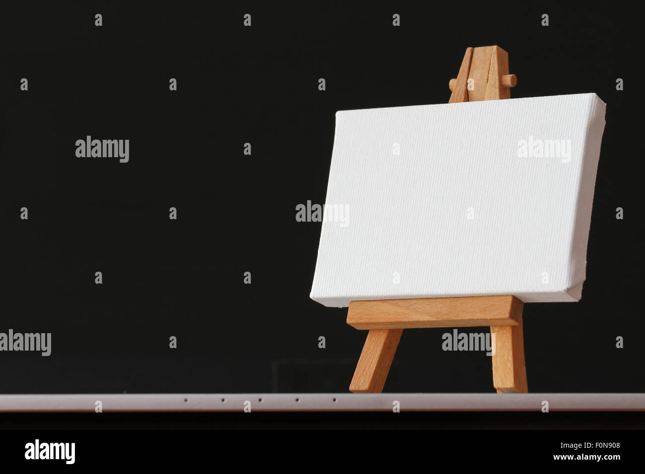 Tela vuota e il cavalletto in legno sul computer portatile come concetto Foto Stock