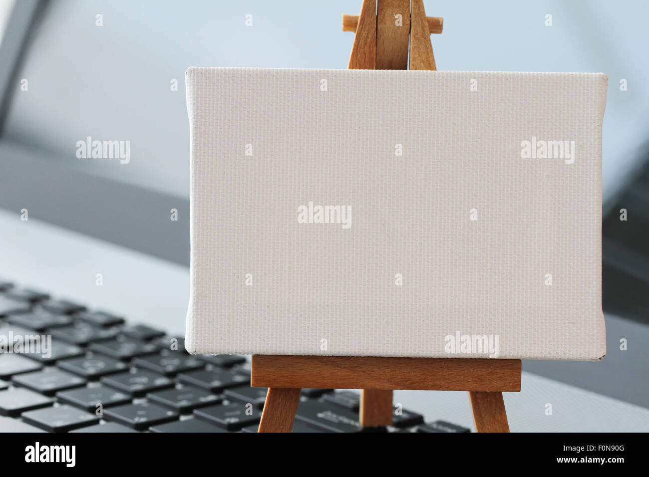 Tela vuota e il cavalletto in legno sul computer portatile come concetto Foto Stock