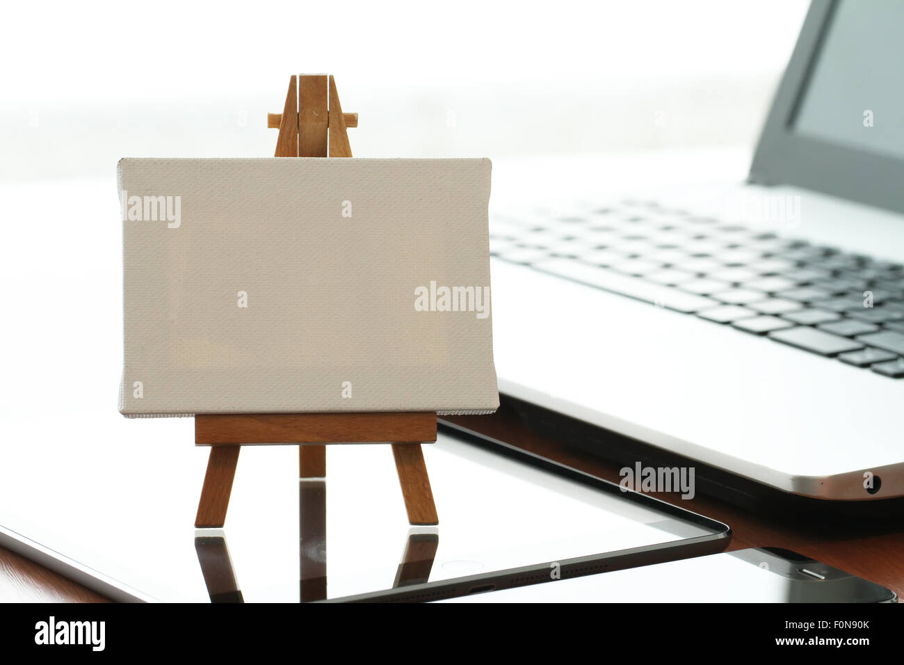 Tela vuota e il cavalletto in legno sul computer portatile come concetto Foto Stock