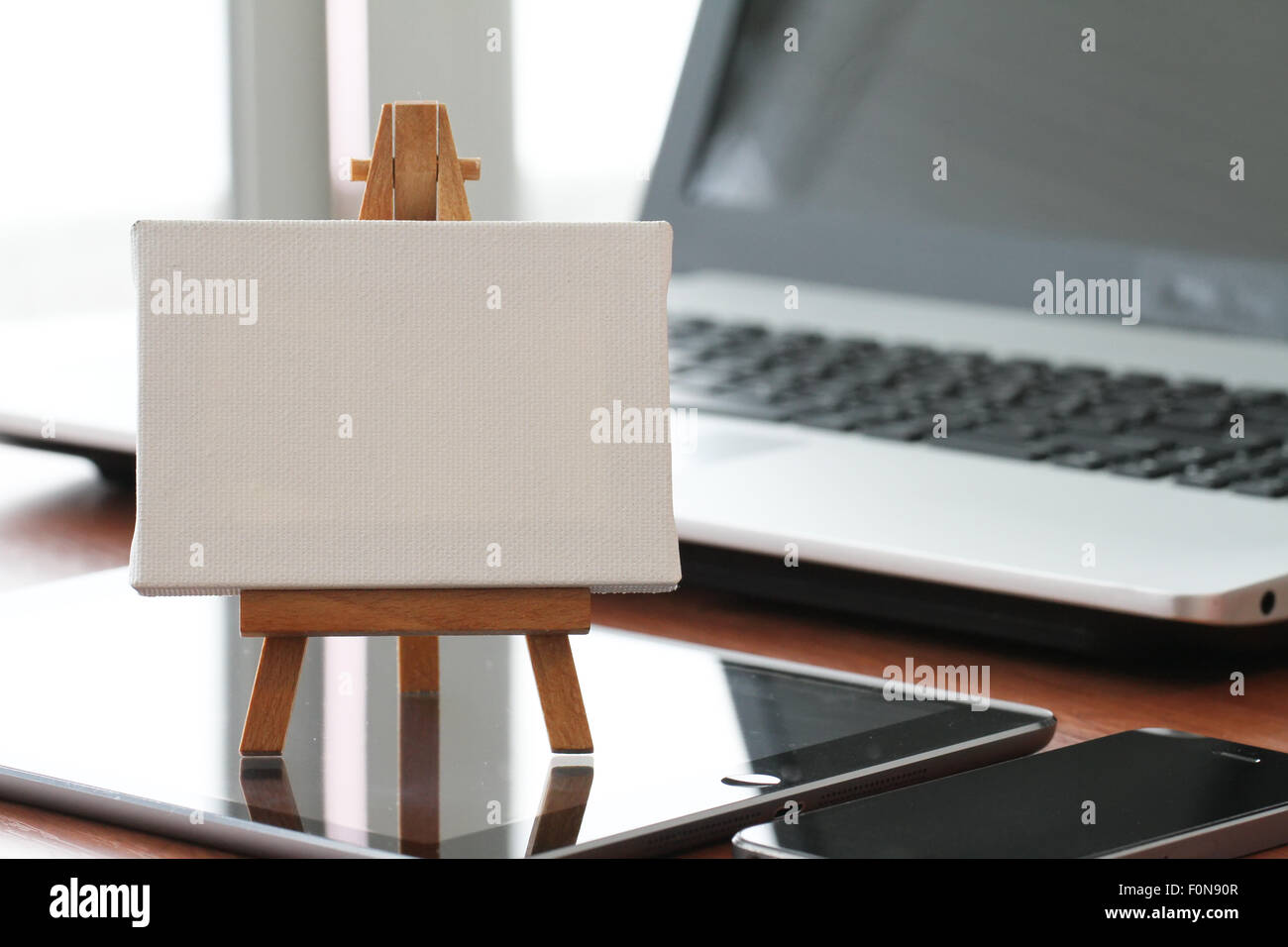 Tela vuota e il cavalletto in legno sul computer portatile come concetto Foto Stock