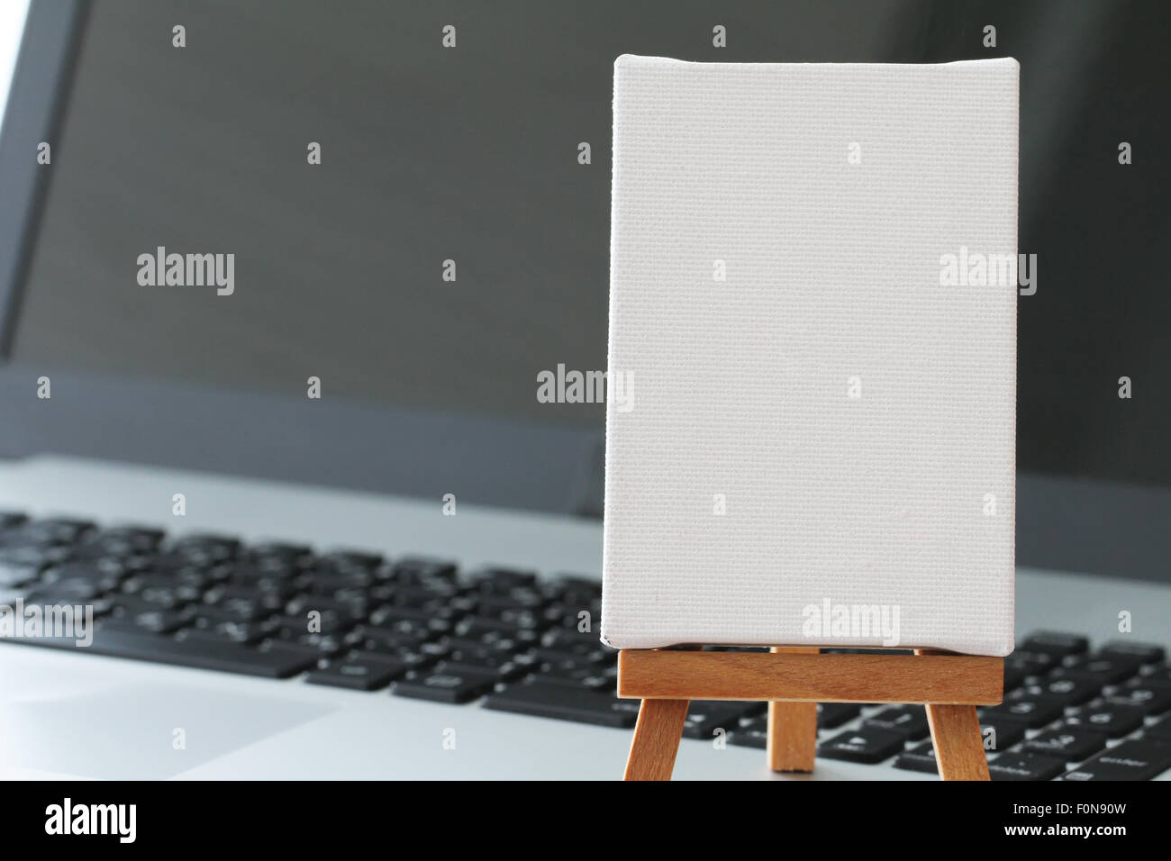 Tela vuota e il cavalletto in legno sul computer portatile come concetto Foto Stock