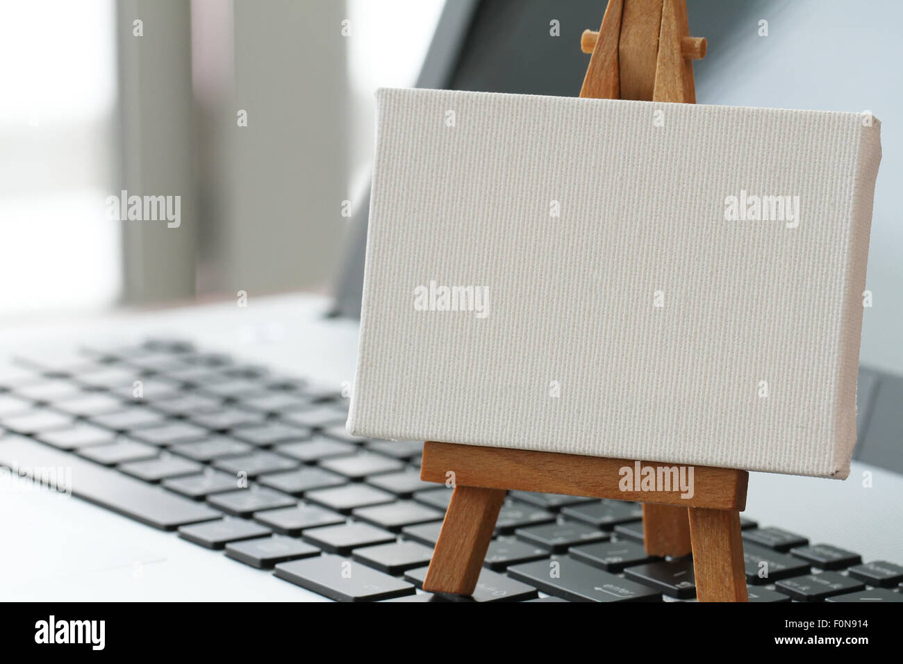 Tela vuota e il cavalletto in legno sul computer portatile come concetto Foto Stock