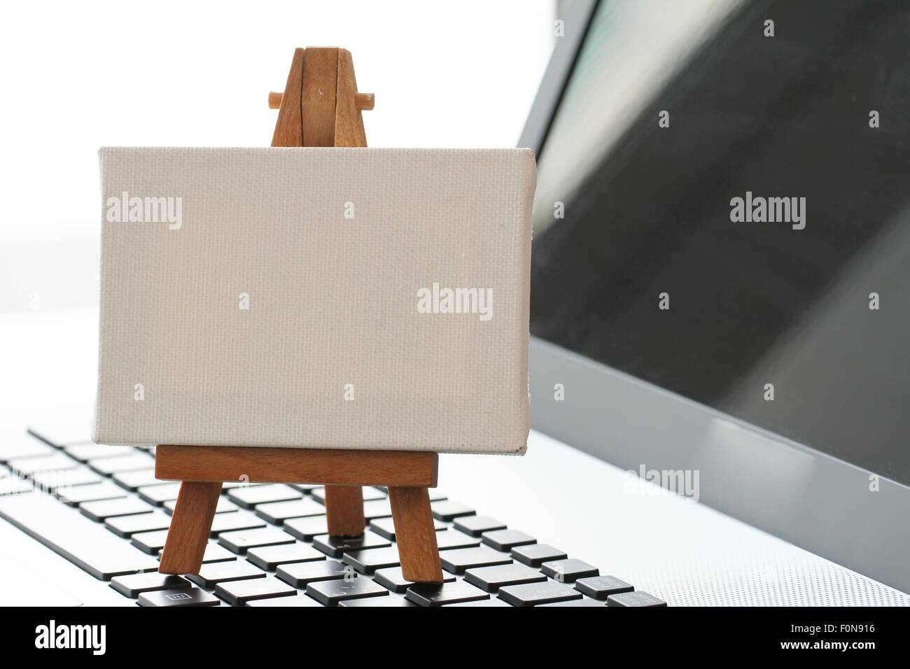 Tela vuota e il cavalletto in legno sul computer portatile come concetto Foto Stock
