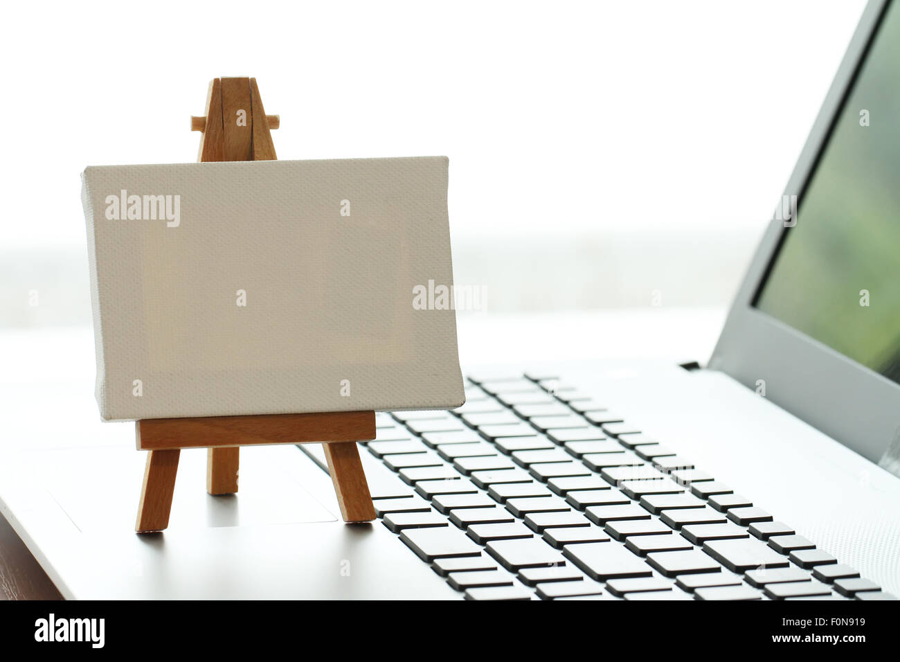 Tela vuota e il cavalletto in legno sul computer portatile come concetto Foto Stock
