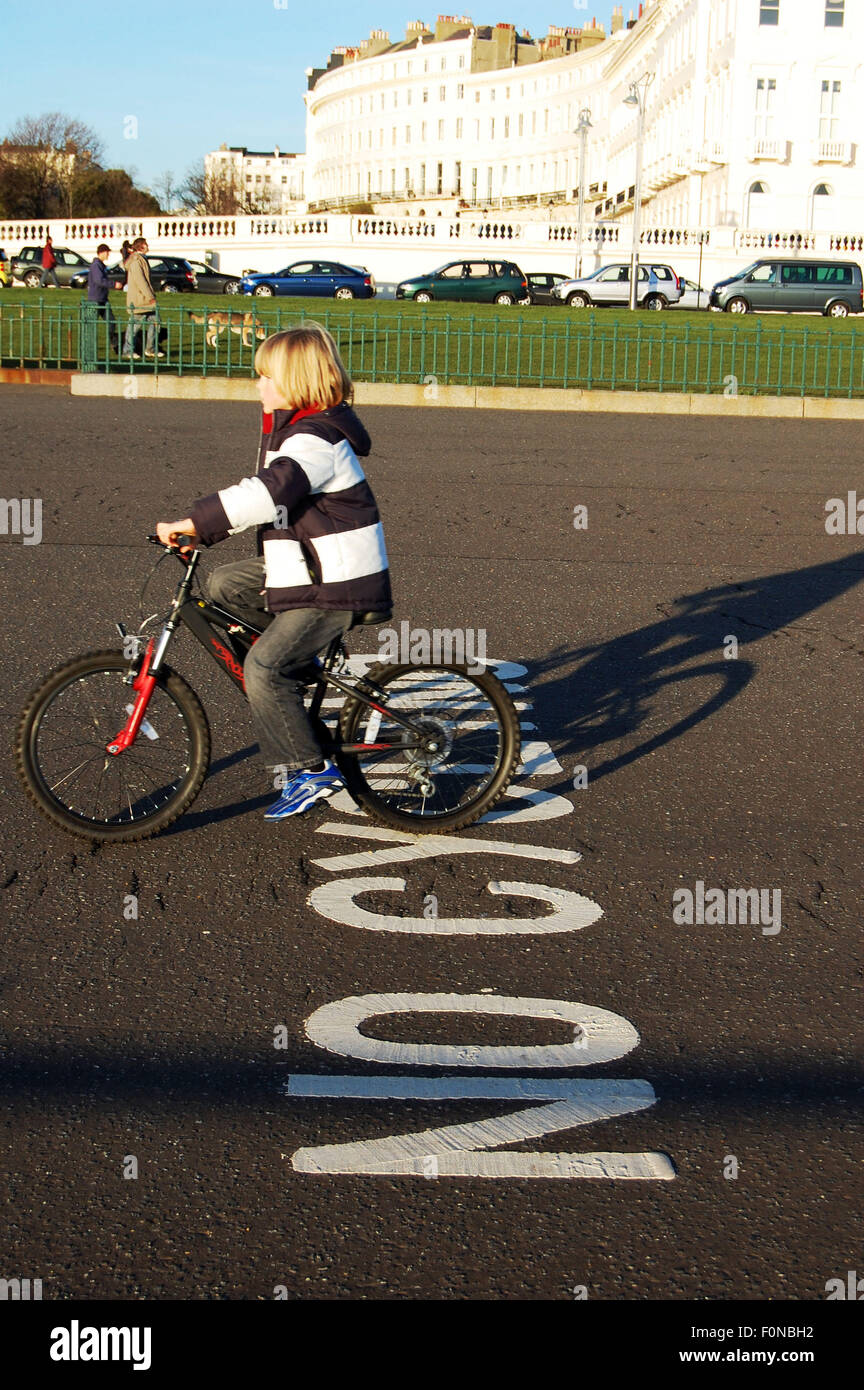 Un bambino ignorando un nessun segno di ciclismo dipinta sul lungomare di Hove Regno Unito Foto Stock