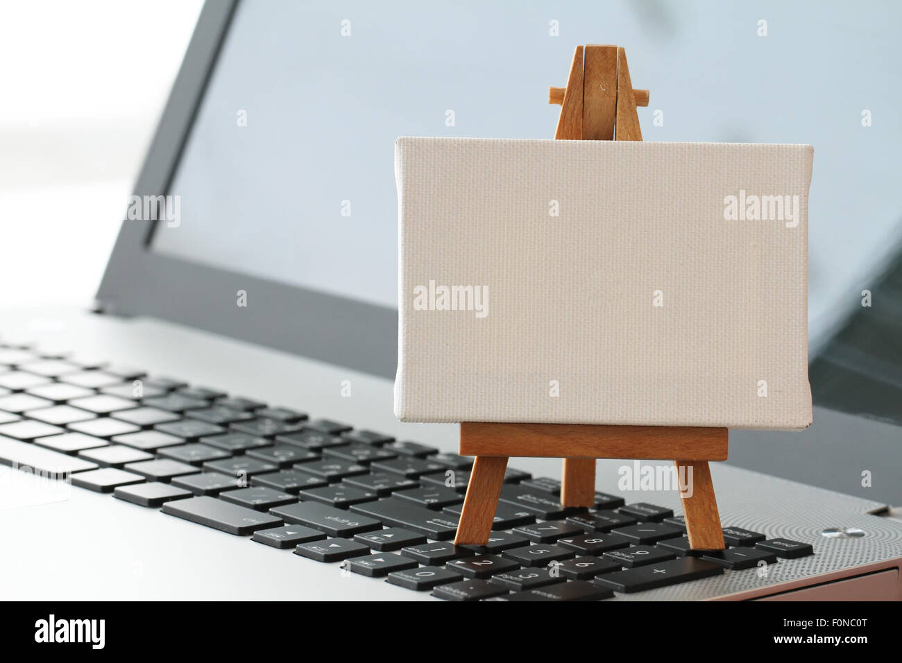Tela vuota e il cavalletto in legno sul computer portatile come concetto Foto Stock