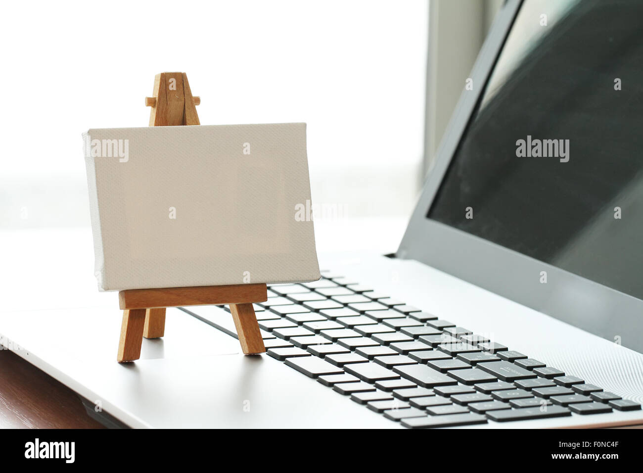 Tela vuota e il cavalletto in legno sul computer portatile come concetto Foto Stock