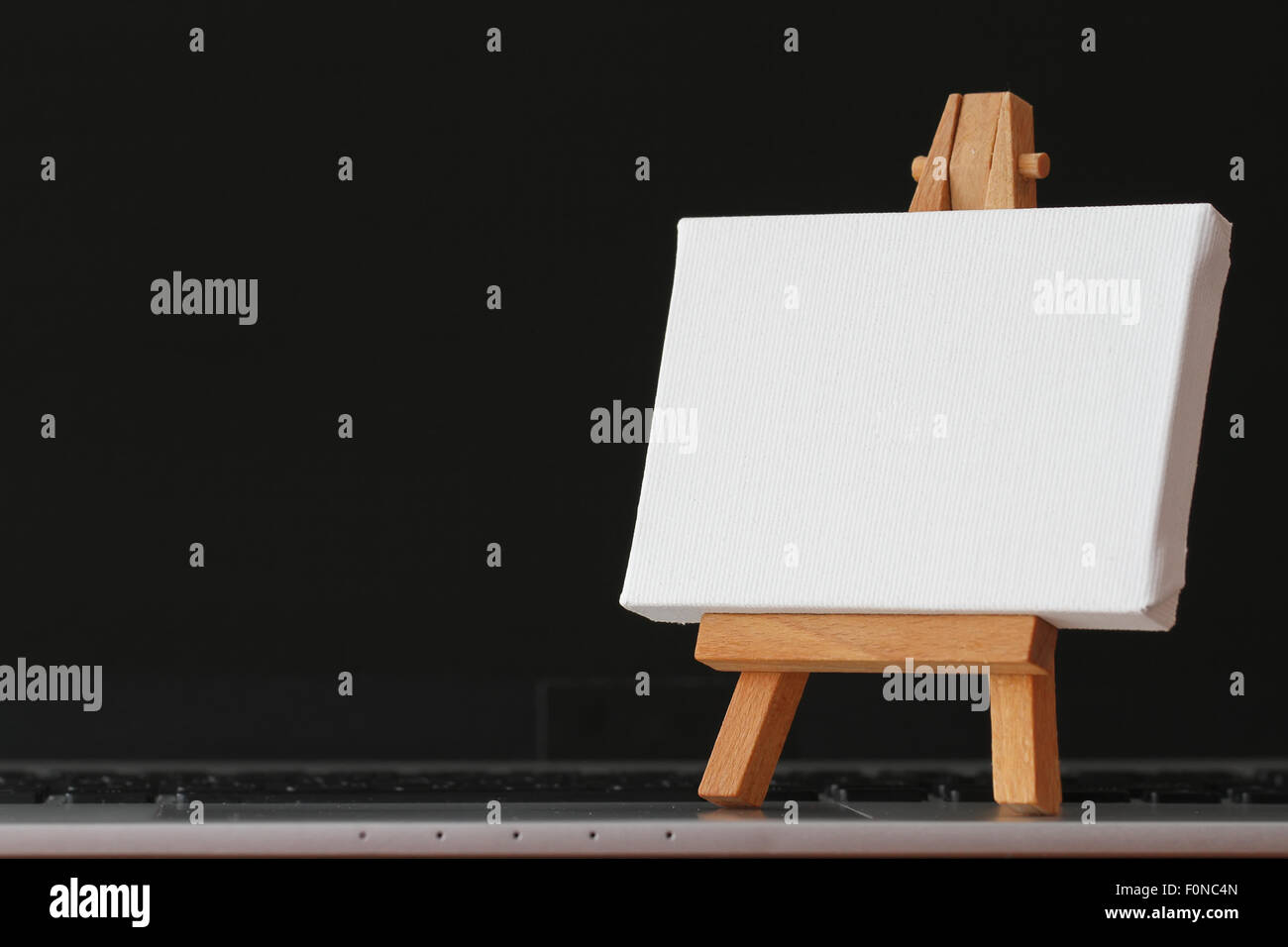 Tela vuota e il cavalletto in legno sul computer portatile come concetto Foto Stock