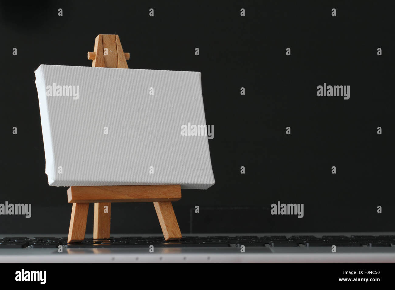 Tela vuota e il cavalletto in legno sul computer portatile come concetto Foto Stock