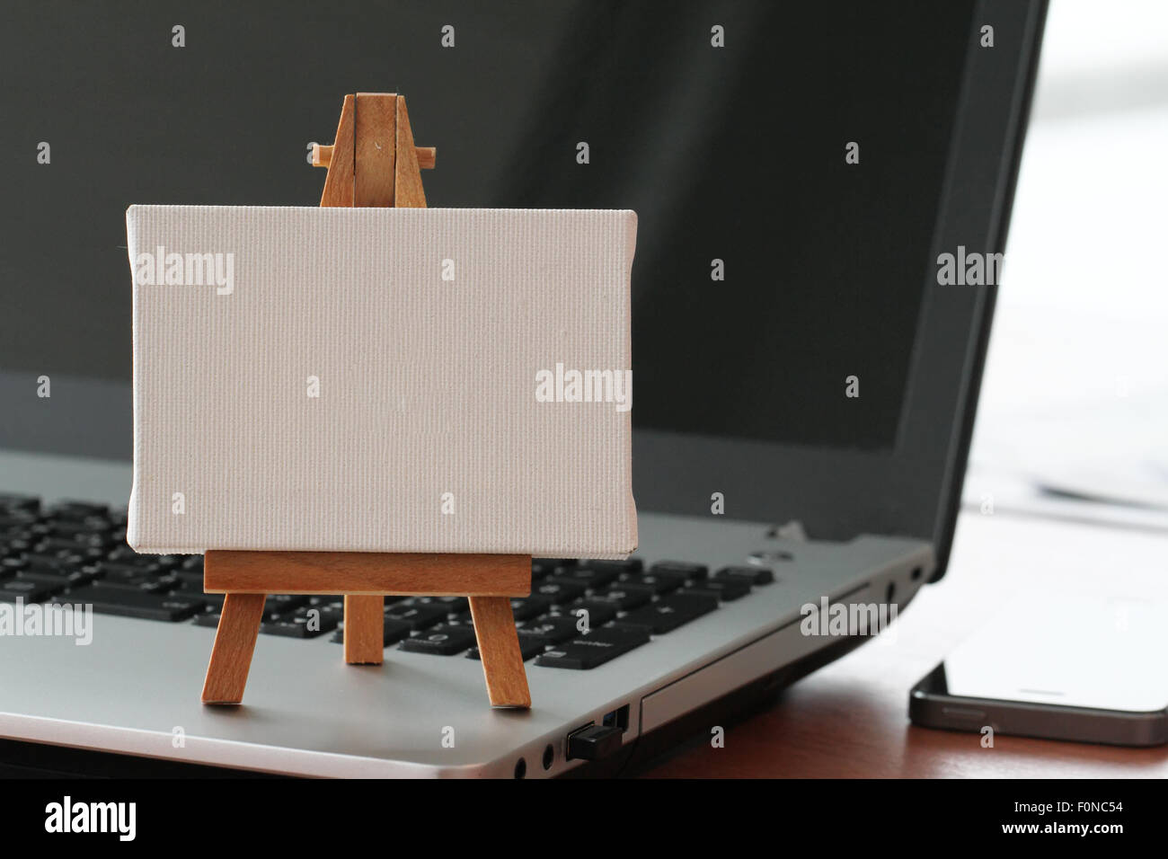 Tela vuota e il cavalletto in legno sul computer portatile come concetto Foto Stock