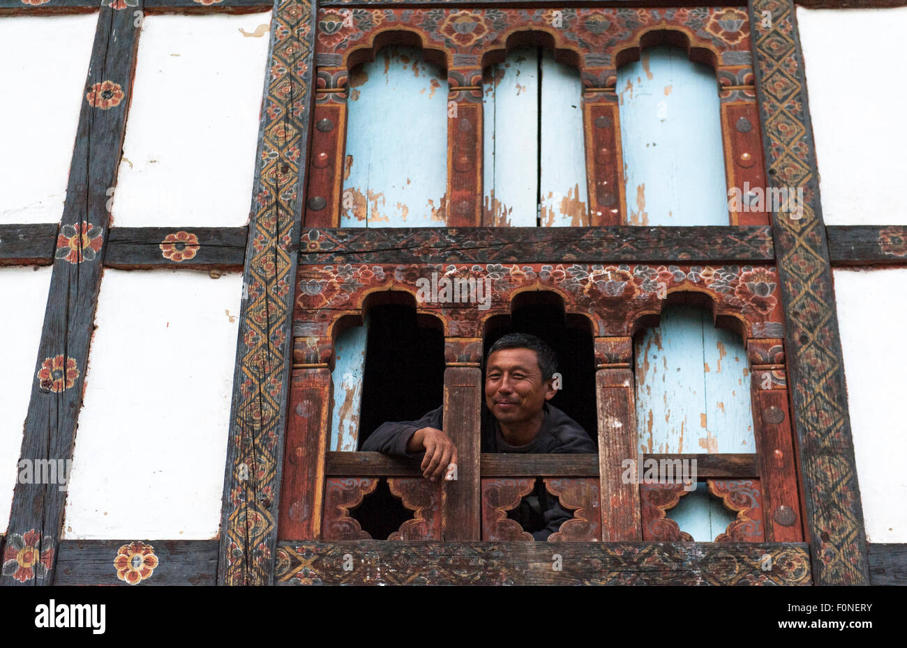 Uomo bhutanesi dalla finestra tradizionale casa di campagna Punakha Buthan Foto Stock