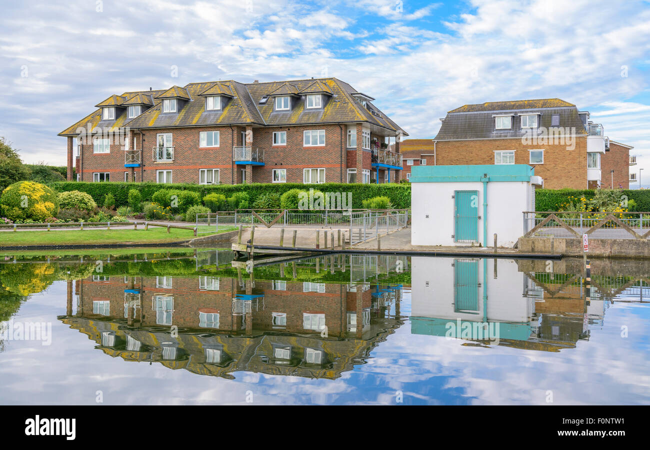 Grande e moderno blocco di appartamenti a riflettere in un lago in mare Strada in Littlehampton, West Sussex, in Inghilterra, Regno Unito. Foto Stock