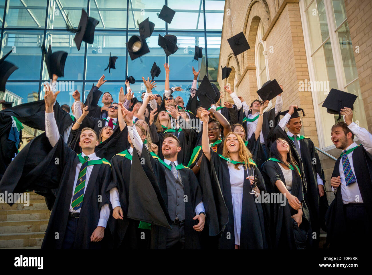 I nuovi diplomati celebrando gettando malta le schede in aria il giorno di graduazione Foto Stock