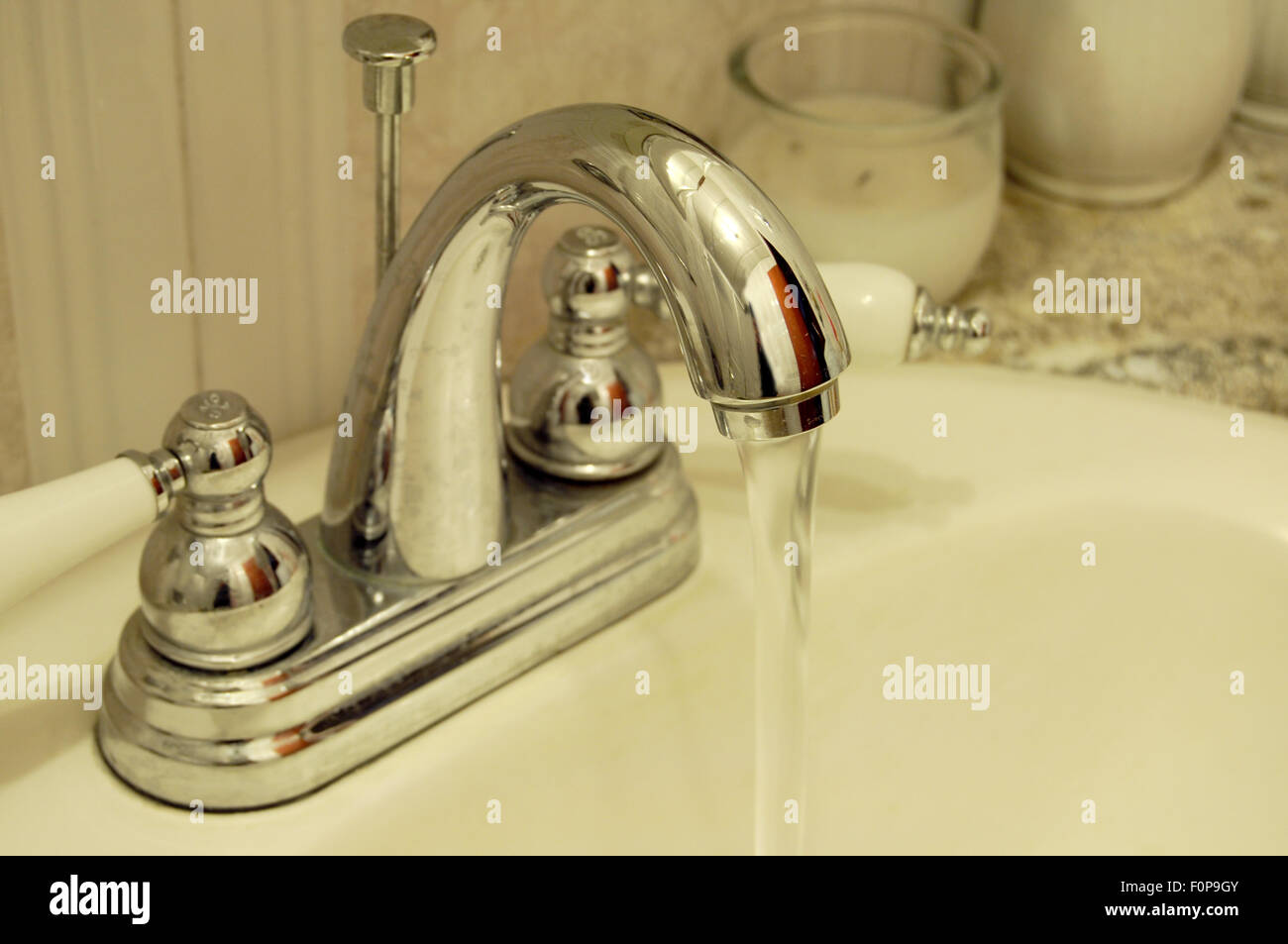 Bagno rubinetto con acqua acceso con una luce dorata guardare Foto Stock