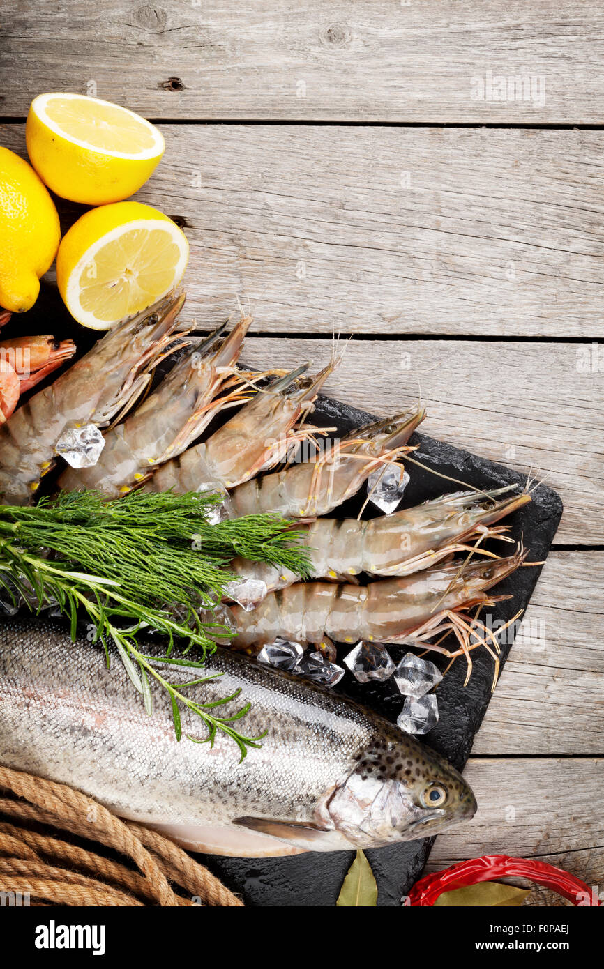 Crudo fresco il cibo del mare con spezie sulla lastra di pietra su un tavolo di legno dello sfondo. Vista superiore Foto Stock
