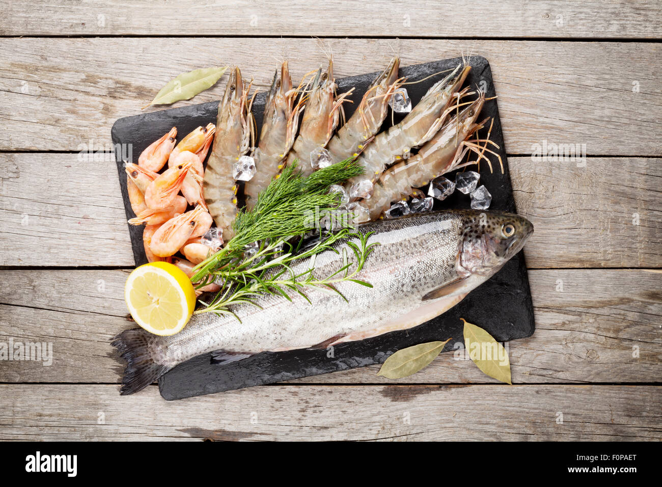 Crudo fresco il cibo del mare con spezie sulla lastra di pietra su un tavolo di legno dello sfondo. Vista superiore Foto Stock