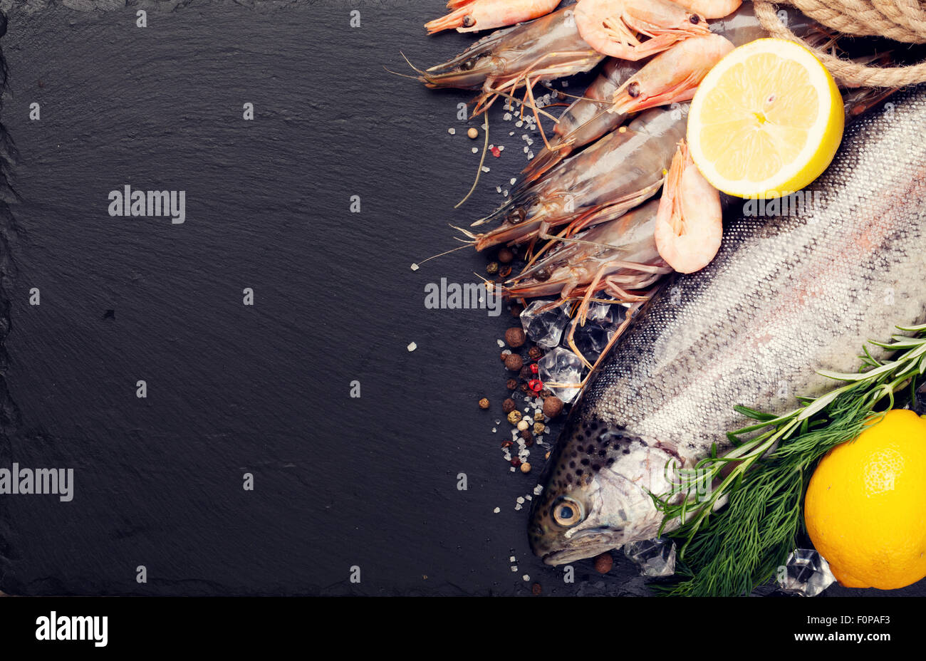 Crudo fresco il cibo del mare con spezie sulla pietra nera dello sfondo. Vista da sopra con copia spazio. Tonica Foto Stock