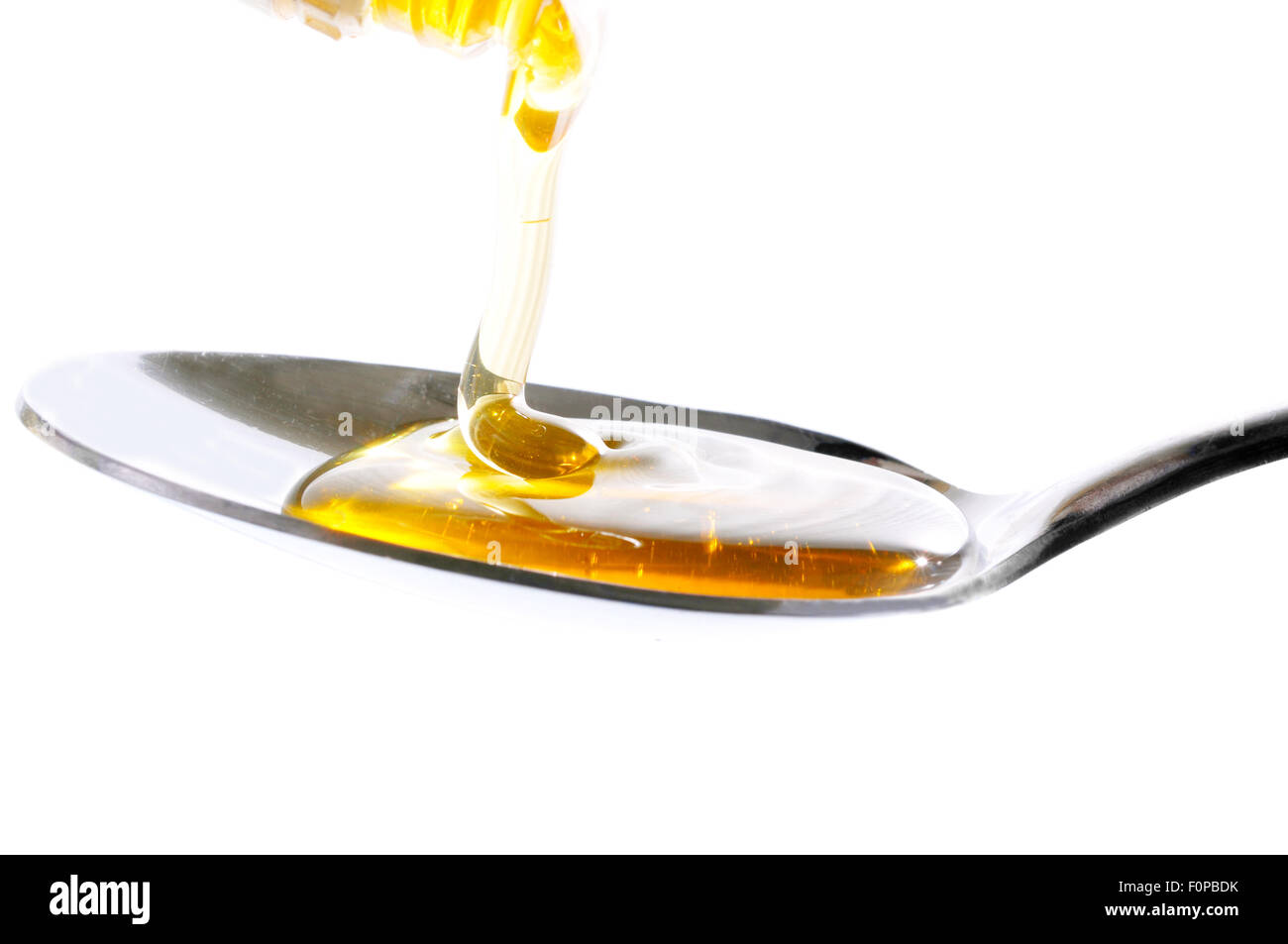 Il miele che cade su di un cucchiaio isolato su uno sfondo bianco Foto Stock