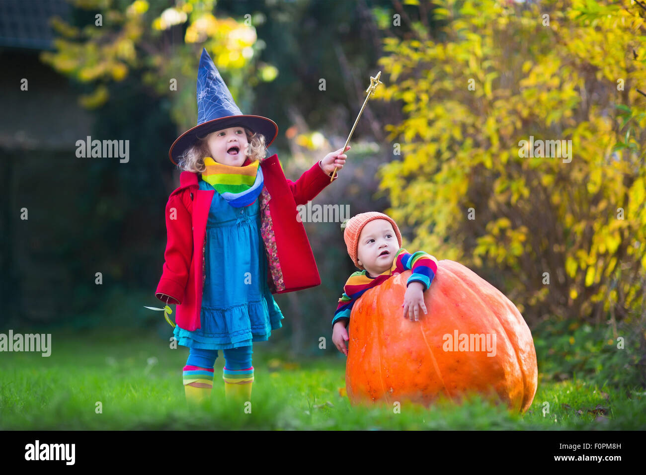 Bambina in costume da strega e baby boy in zucca enorme giocando in autunno park. I bambini di Halloween dolcetto o scherzetto. Foto Stock