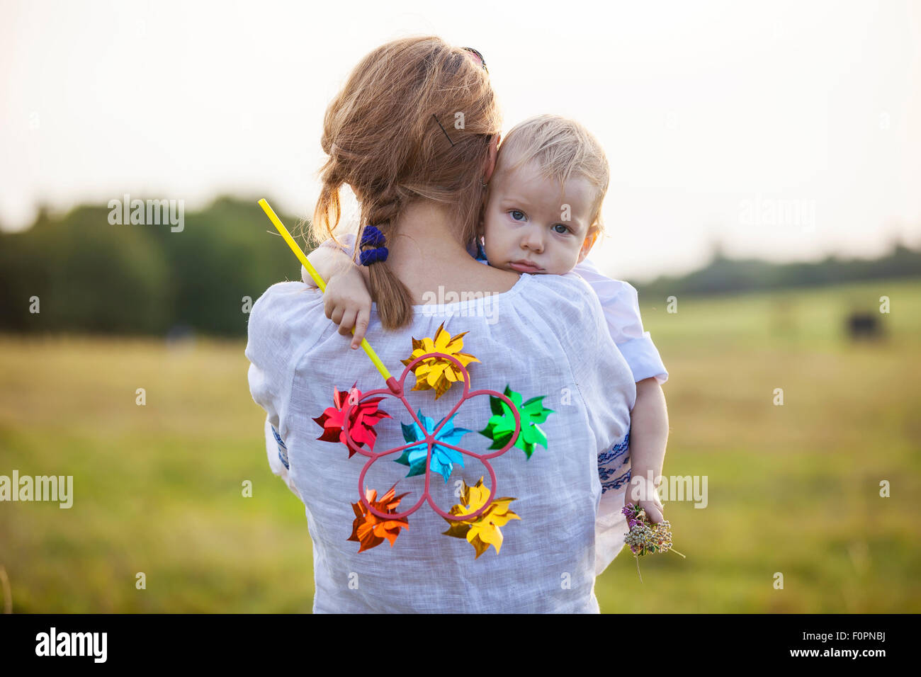 Giovane donna caucasica portando stanco toddler figlio all'aperto Foto Stock