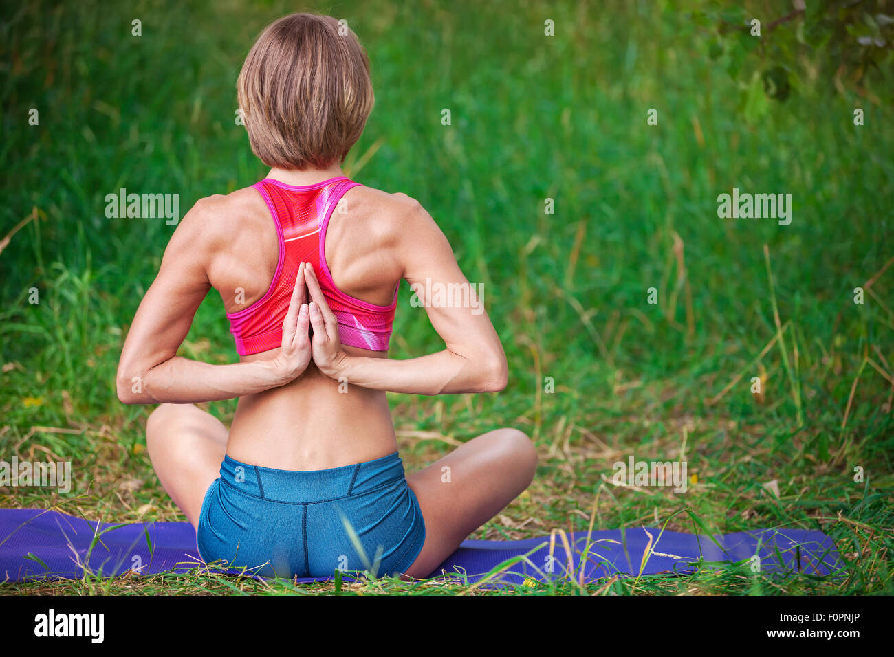 Giovane donna caucasica meditando nella posizione del loto all'aperto Foto Stock