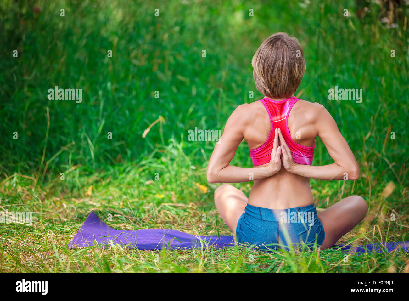Giovane donna caucasica meditando nella posizione del loto all'aperto Foto Stock
