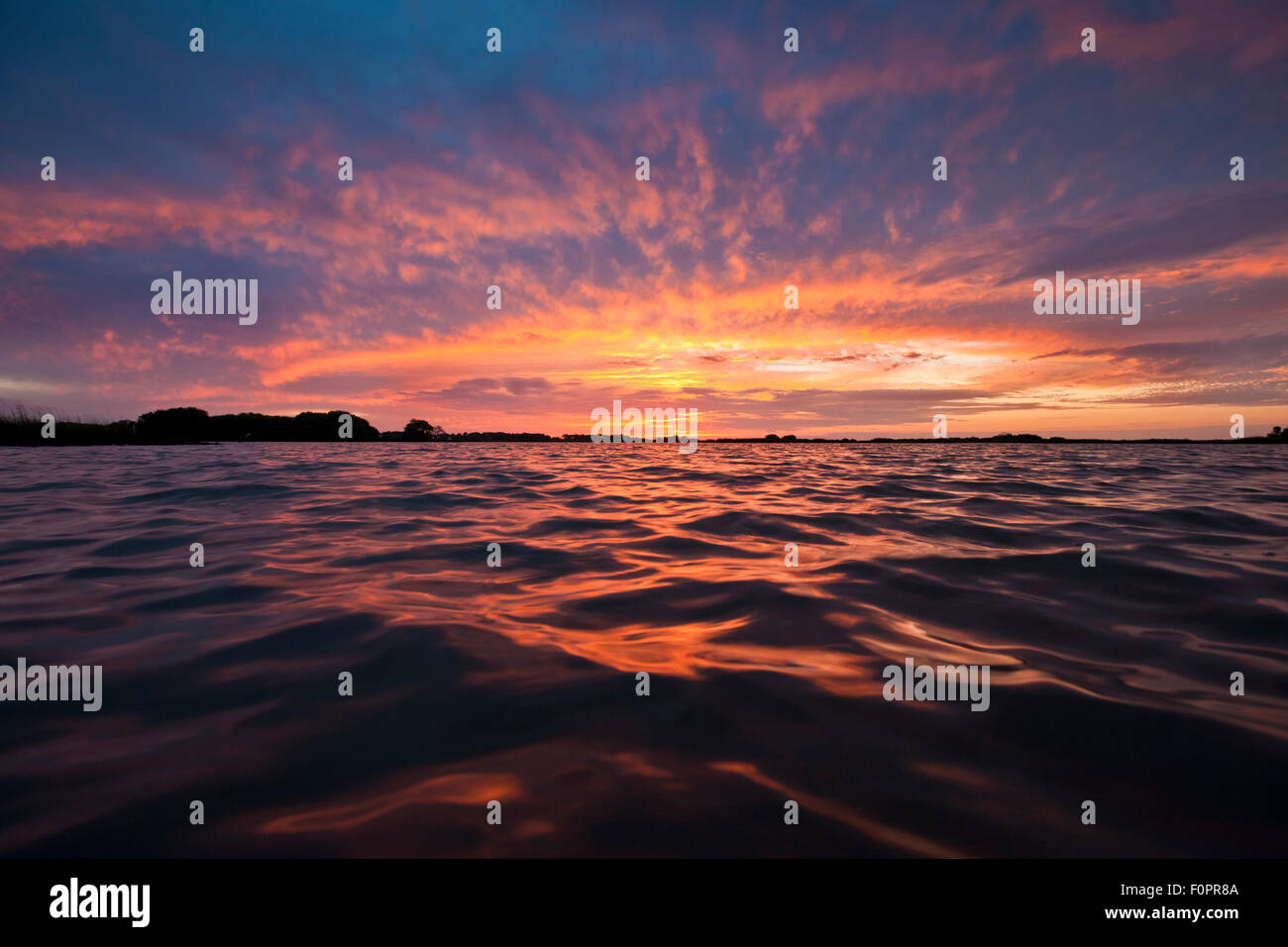 Esplosione del tramonto visto dalla linea di acqua sul Golfo del Messico Foto Stock