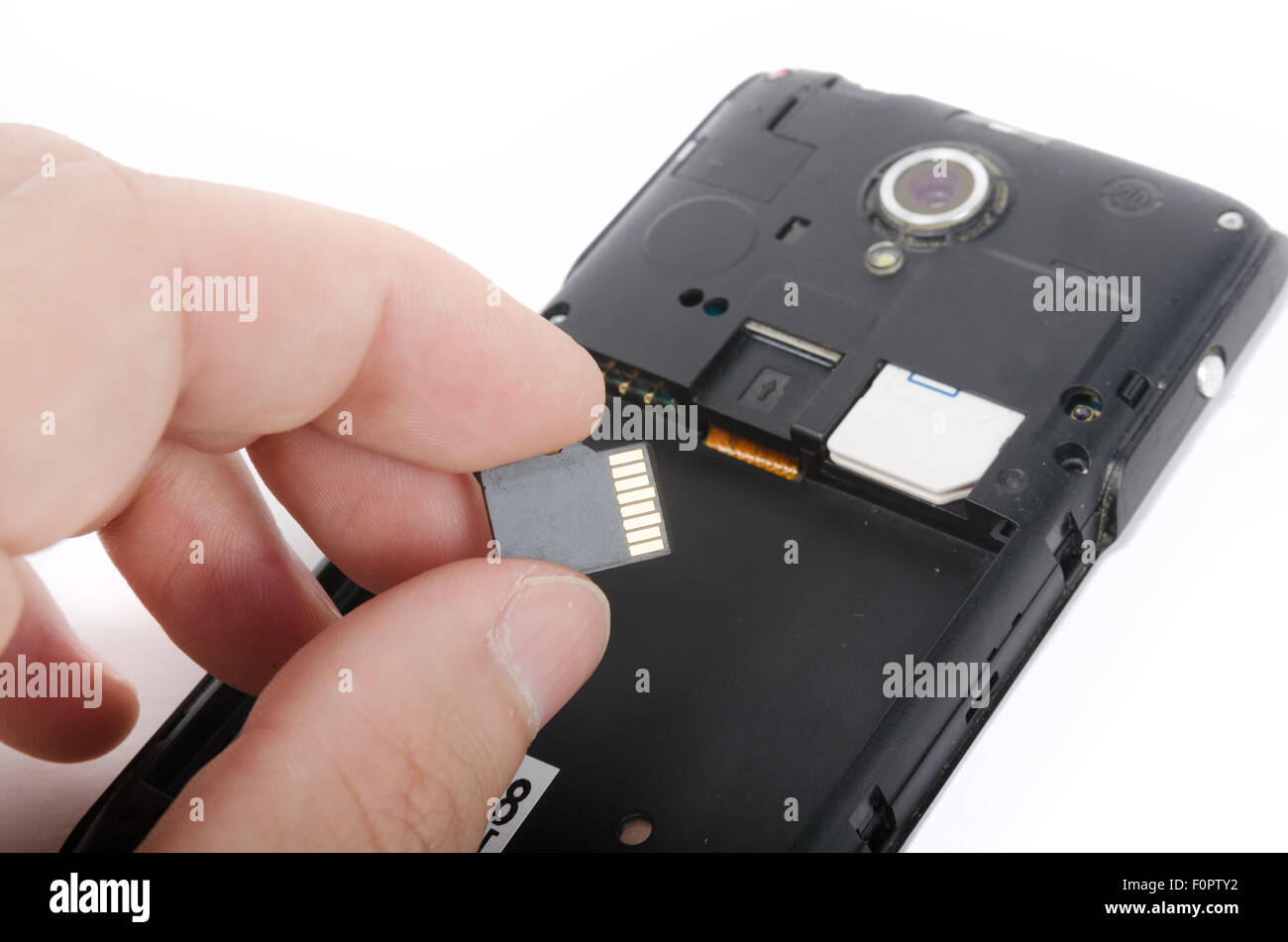 Mano umana inserendo la scheda Micro SD nel telefono cellulare (smartphone) Foto Stock