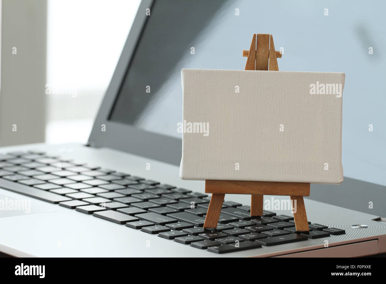 Tela vuota e il cavalletto in legno sul computer portatile come concetto Foto Stock