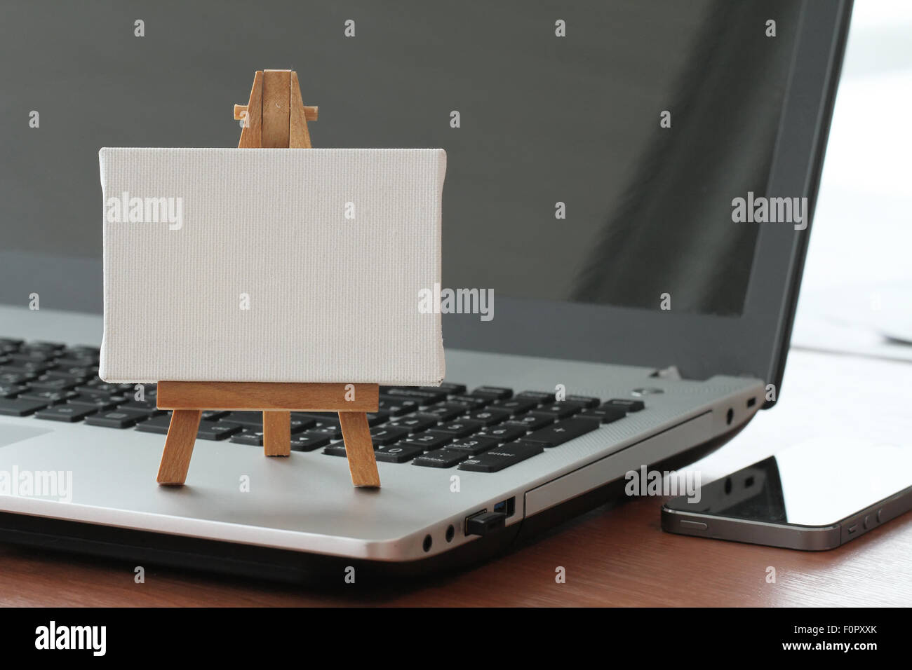 Tela vuota e il cavalletto in legno sul computer portatile come concetto Foto Stock