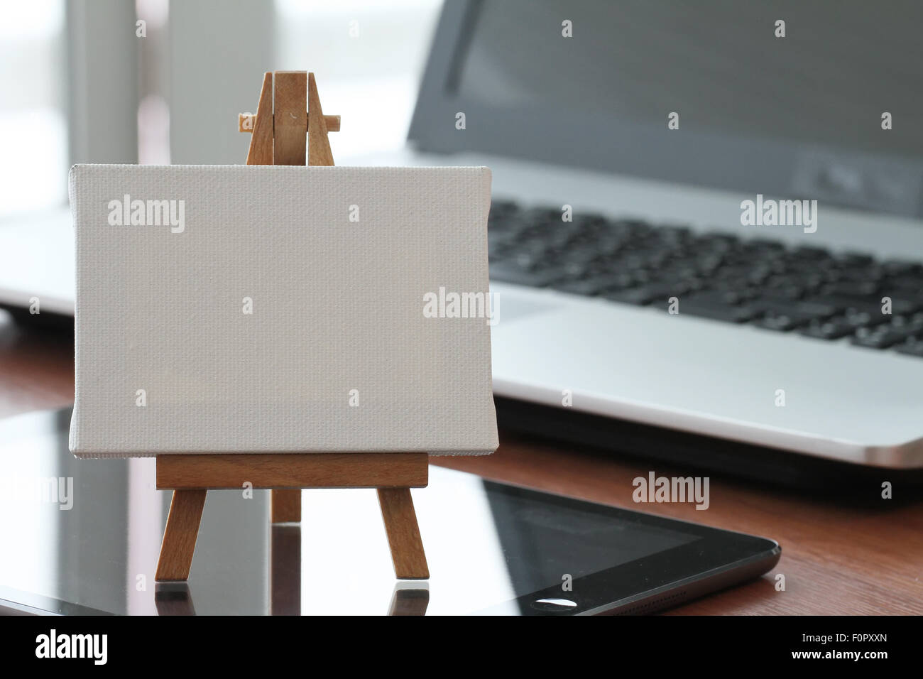 Tela vuota e il cavalletto in legno sul computer portatile come concetto Foto Stock