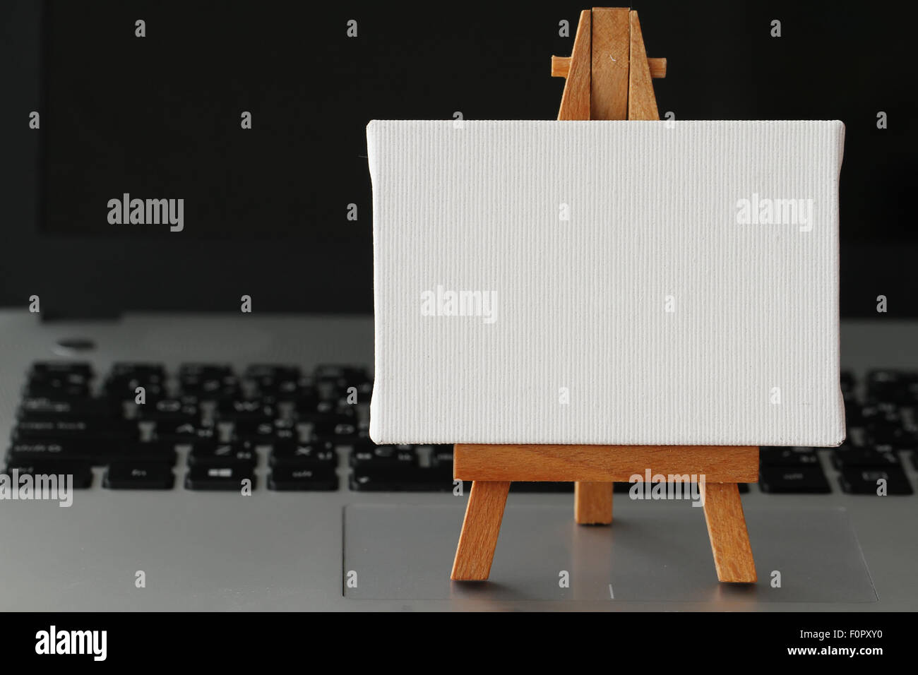 Tela vuota e il cavalletto in legno sul computer portatile come concetto Foto Stock