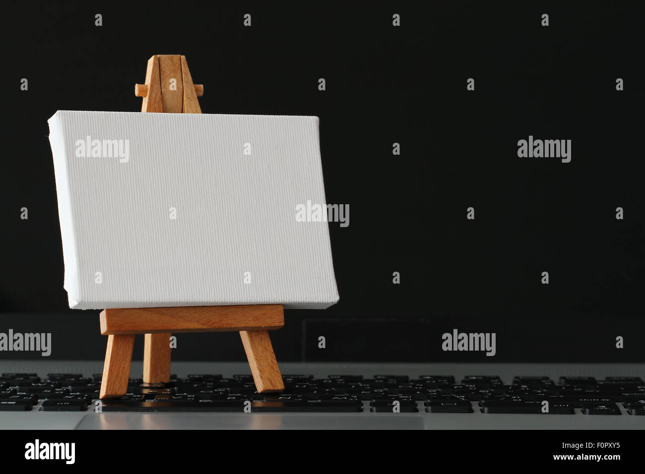 Tela vuota e il cavalletto in legno sul computer portatile come concetto Foto Stock
