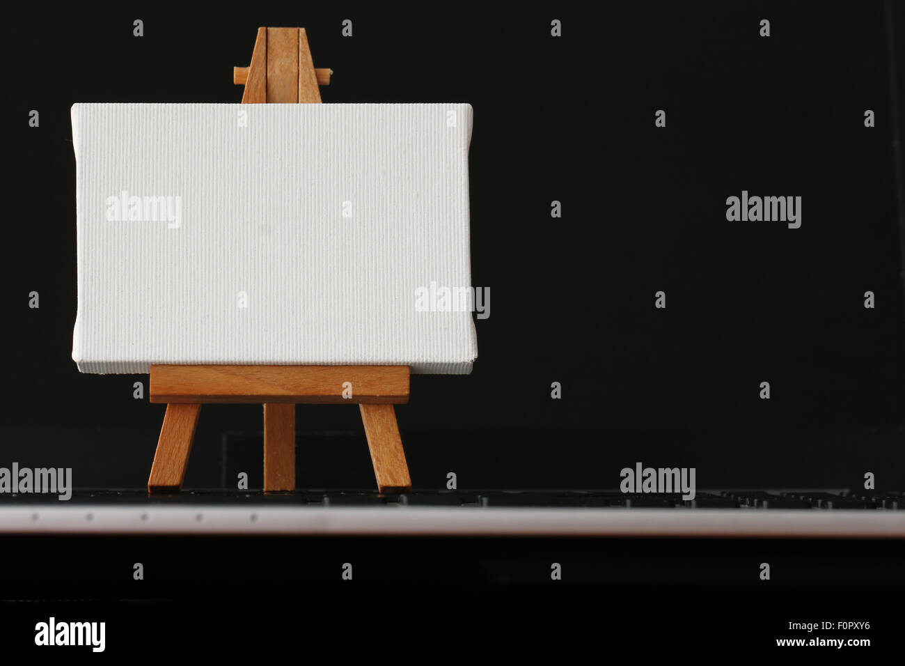 Tela vuota e il cavalletto in legno sul computer portatile come concetto Foto Stock