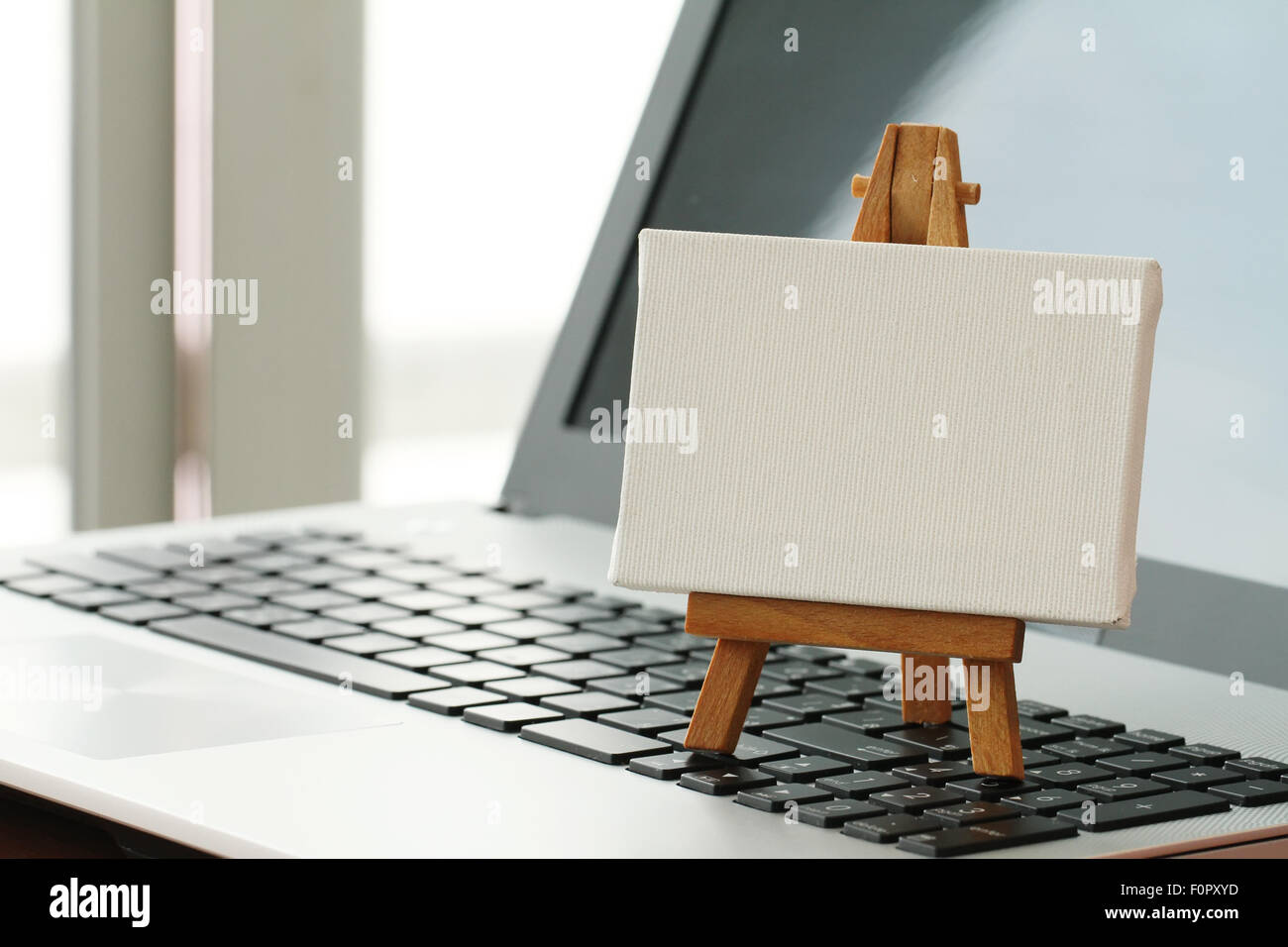 Tela vuota e il cavalletto in legno sul computer portatile come concetto Foto Stock