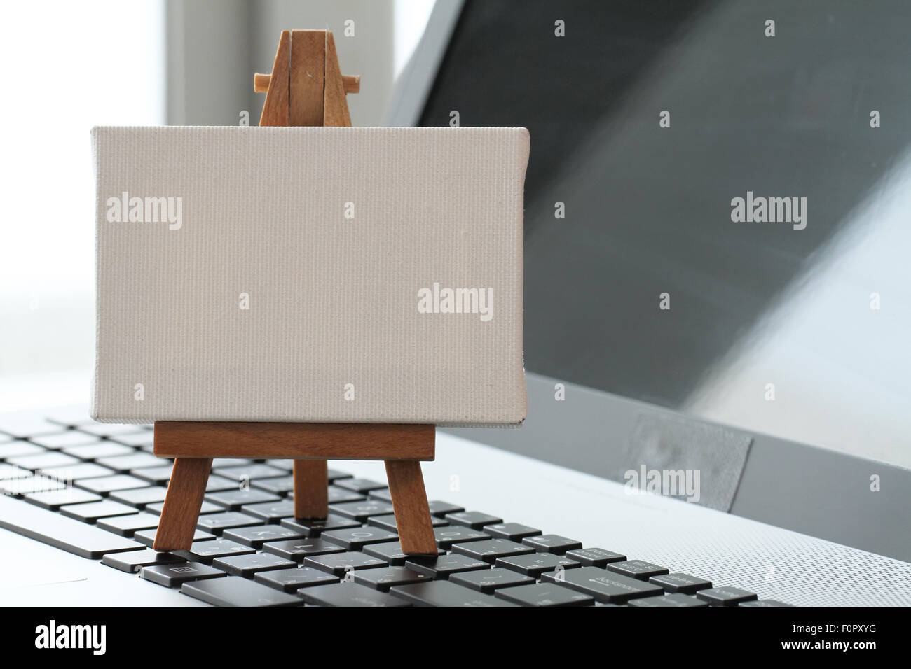 Tela vuota e il cavalletto in legno sul computer portatile come concetto Foto Stock