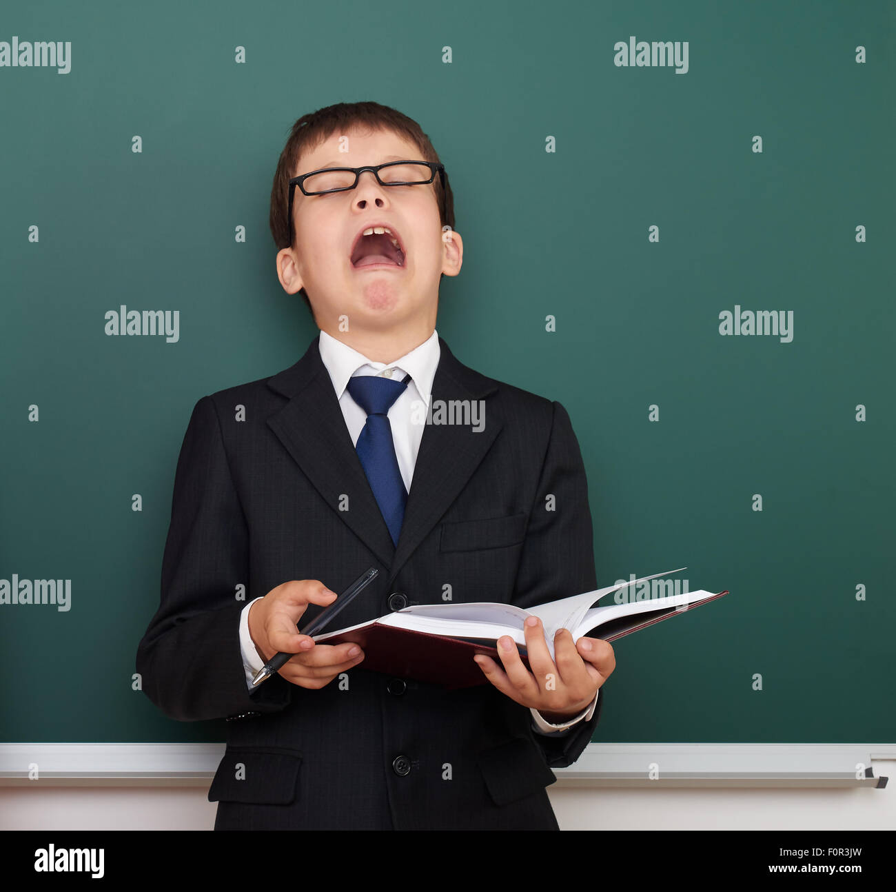 Assonnato ragazzo in tuta sul bordo della scuola sullo sfondo Foto Stock