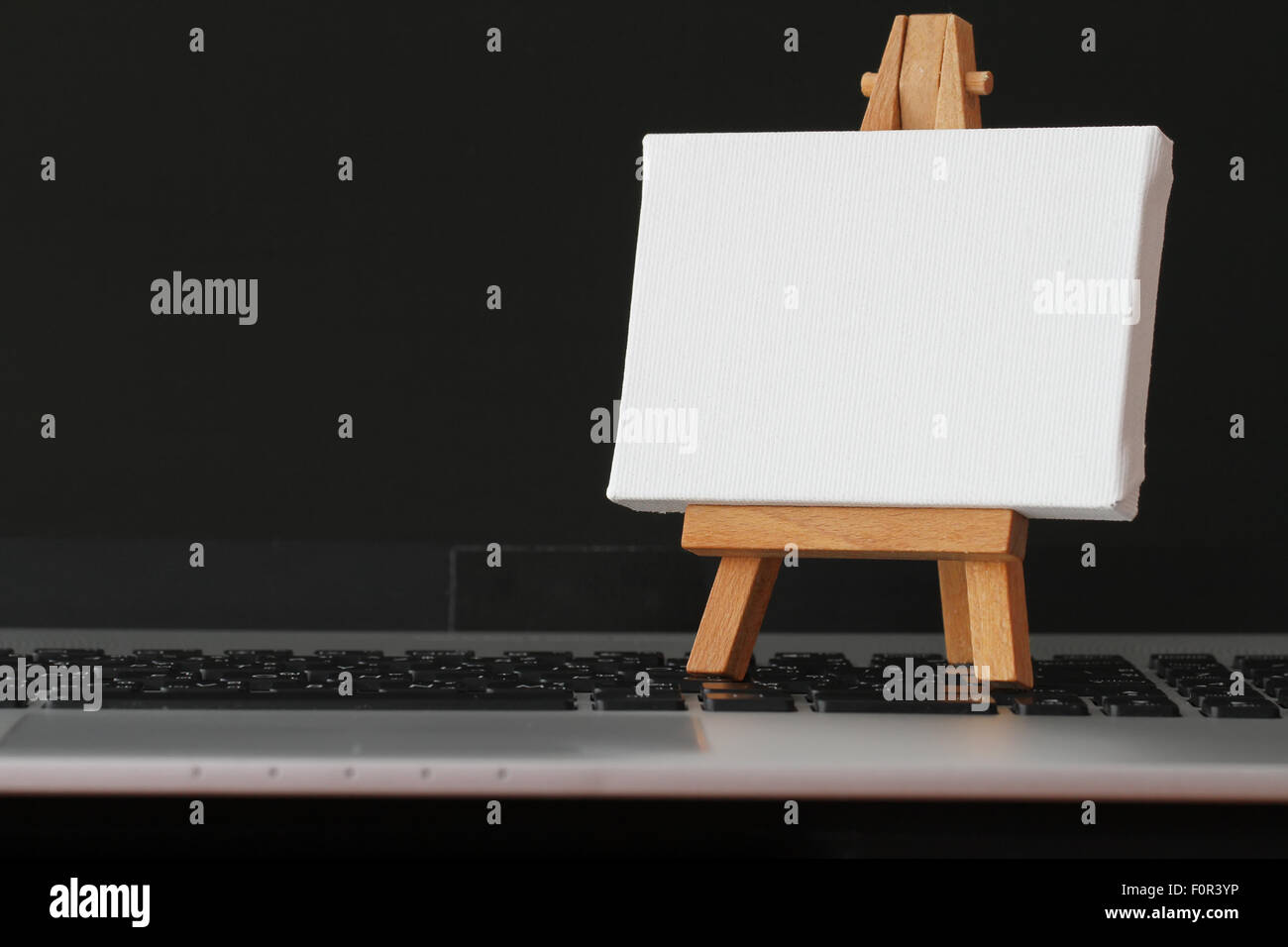 Tela vuota e il cavalletto in legno sul computer portatile come concetto Foto Stock