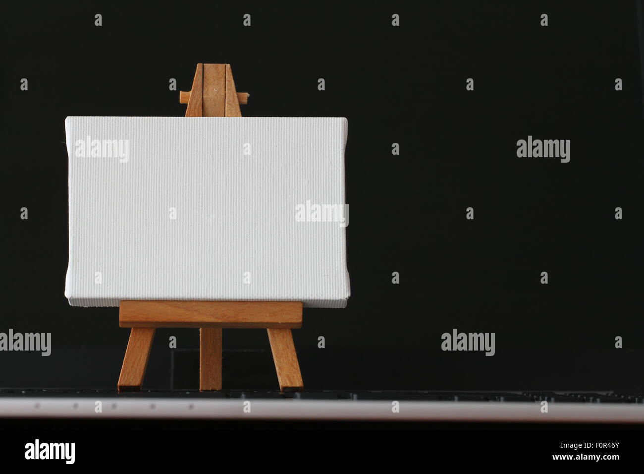 Tela vuota e il cavalletto in legno sul computer portatile come concetto Foto Stock