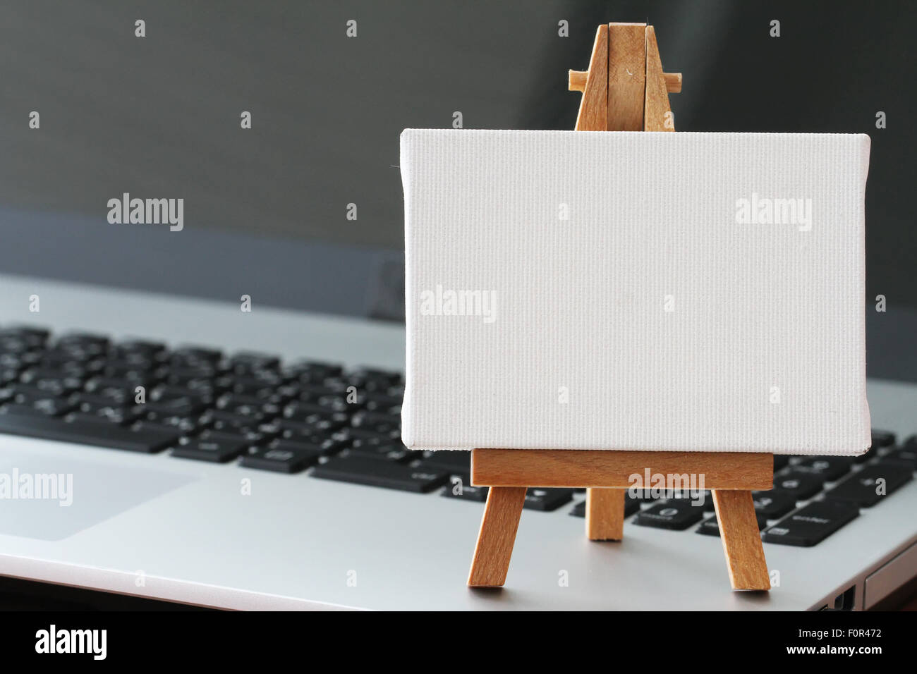 Tela vuota e il cavalletto in legno sul computer portatile come concetto Foto Stock