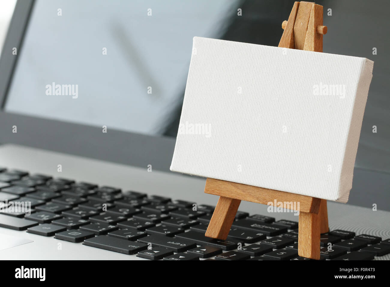 Tela vuota e il cavalletto in legno sul computer portatile come concetto Foto Stock