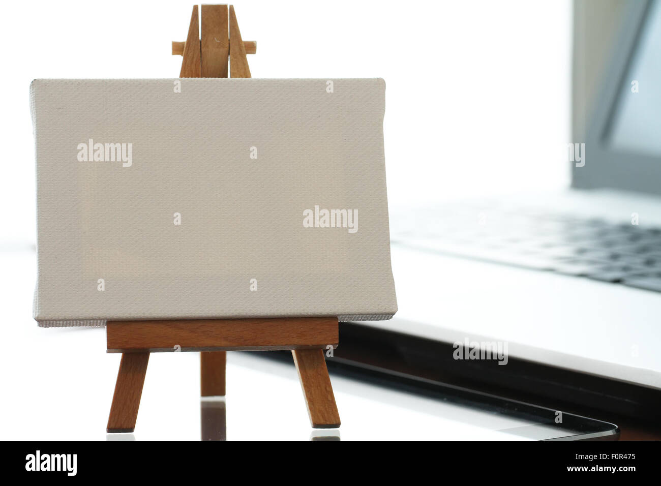 Tela vuota e il cavalletto in legno sul computer portatile come concetto Foto Stock