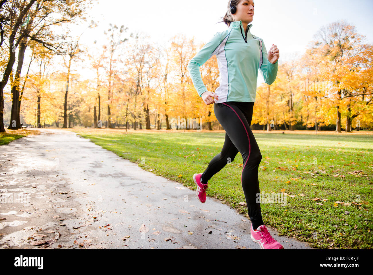 Giovane Donna con cuffie jogging in autunno la natura e ascolto di musica Foto Stock