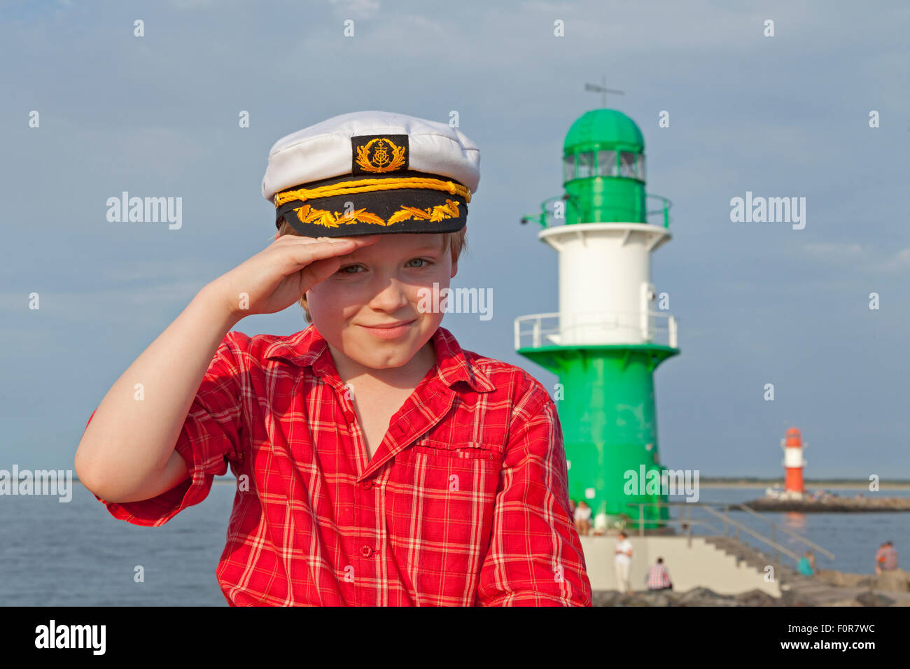 Giovane capitano salutando nella parte anteriore del faro, Warnemuende, Rostock, Meclemburgo-Pomerania Occidentale, Germania Foto Stock