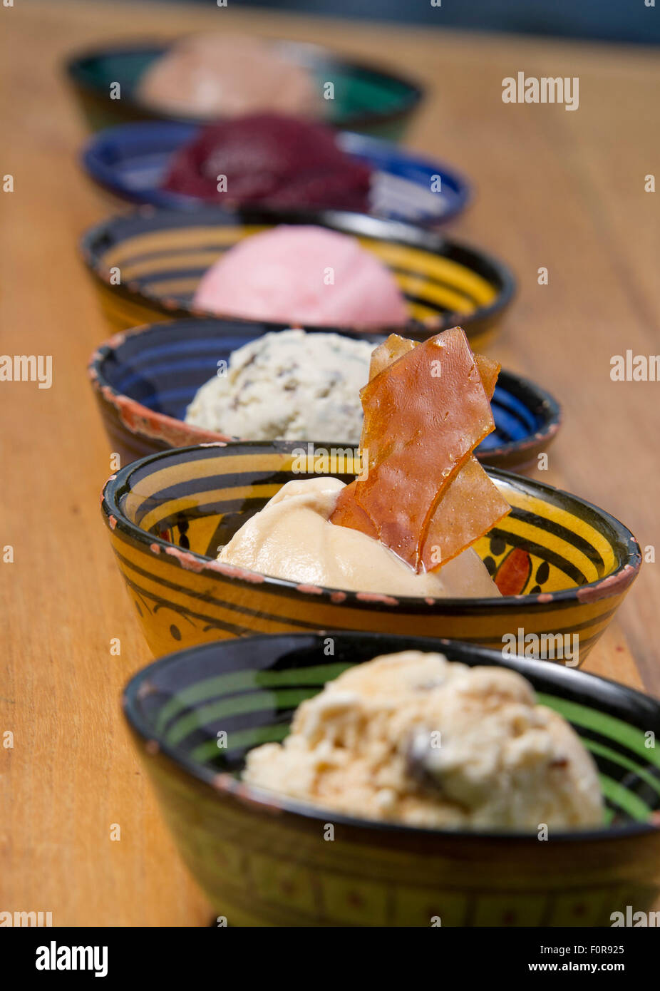 Una selezione di sei gelati con un brandy snap in piatti colorati. Foto Stock