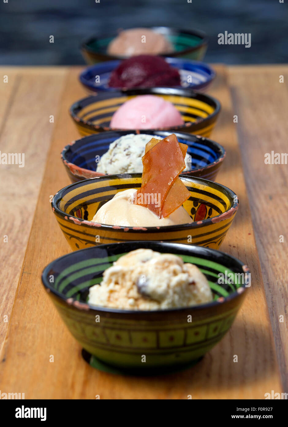 Una selezione di sei gelati con un brandy snap in piatti colorati. Foto Stock