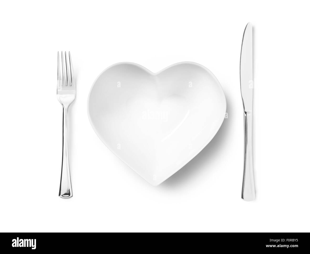 Colpo di cuore una piastra sagomata o ciotola con un argento coltello e forchetta implicando un amore di mangiare sano. L'immagine ha spazio copia un Foto Stock