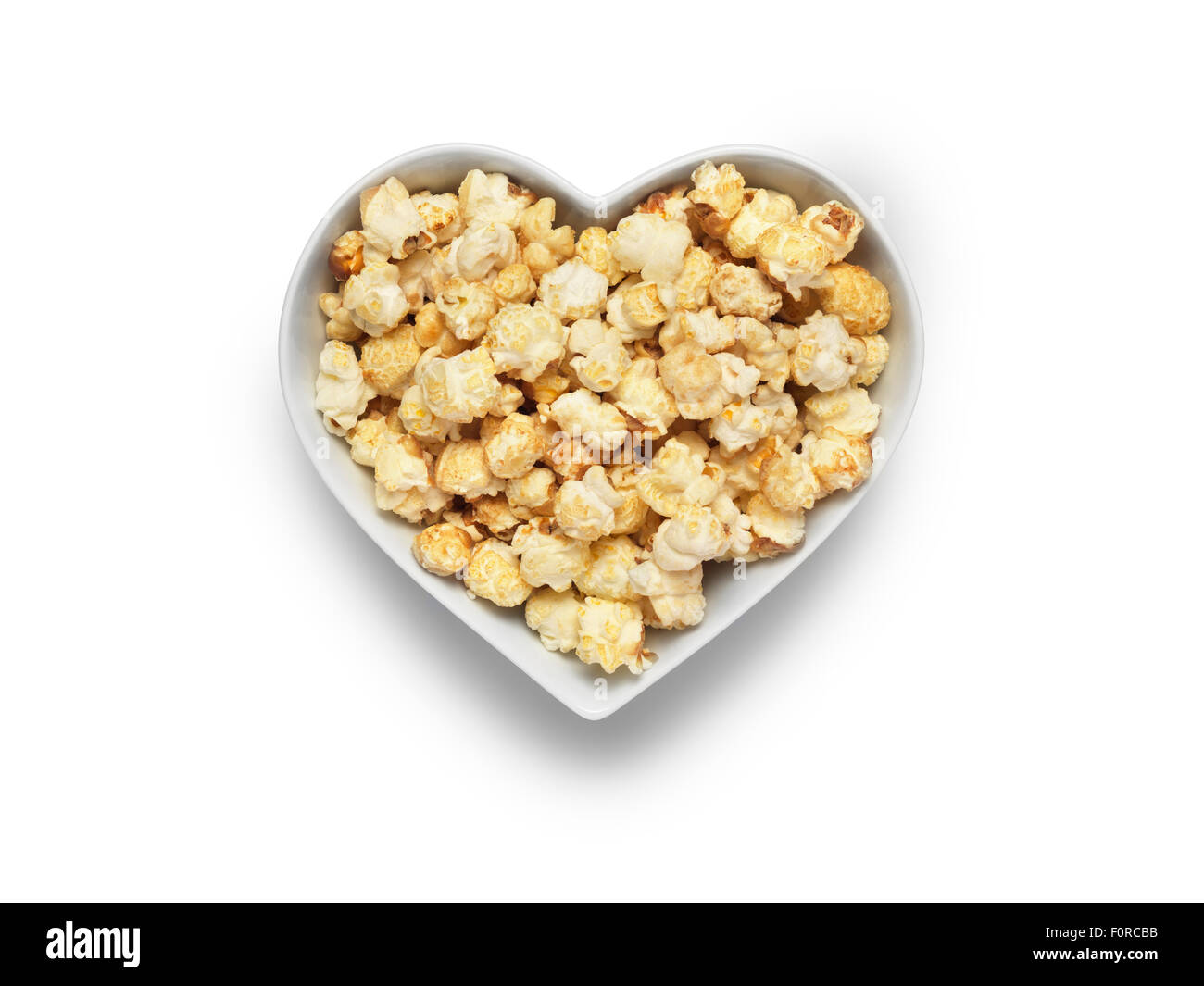 Colpo di stile cinema popcorn in un cuore ciotola sagomata isolata su uno sfondo bianco con un tracciato di ritaglio e copia dello spazio per la d Foto Stock