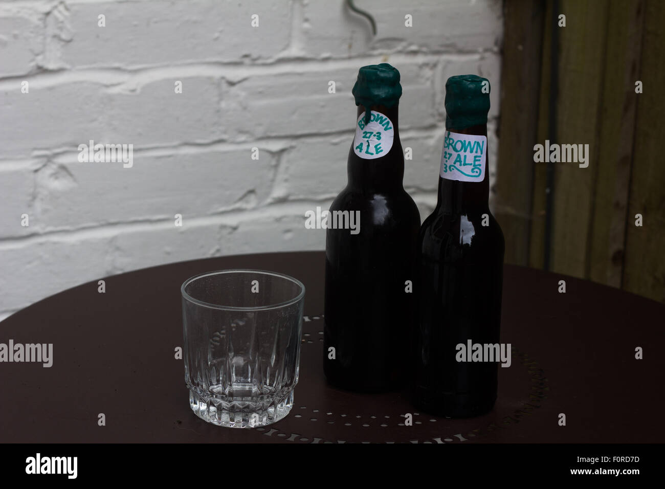 Due bottiglie di home-birra brown ale con un vetro. Foto Stock