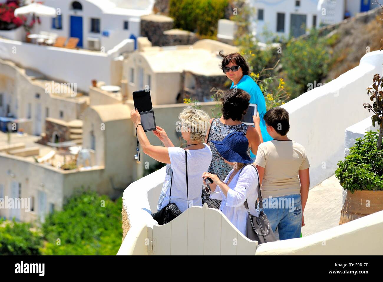 Persone con tenuta in mano tablet pc per prendere le fotografie nel villaggio di Oia Santorini Grecia Foto Stock